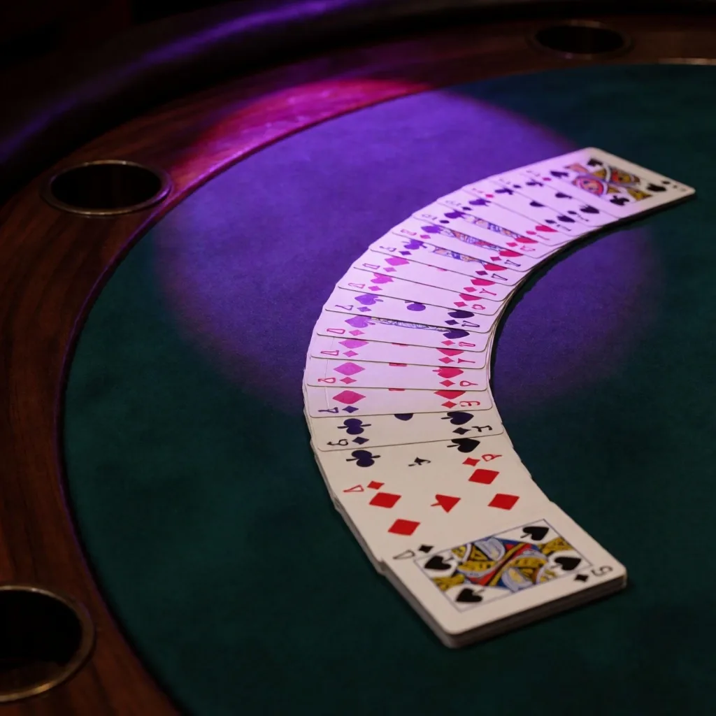 Playing cards fanned on green felt with dramatic lighting