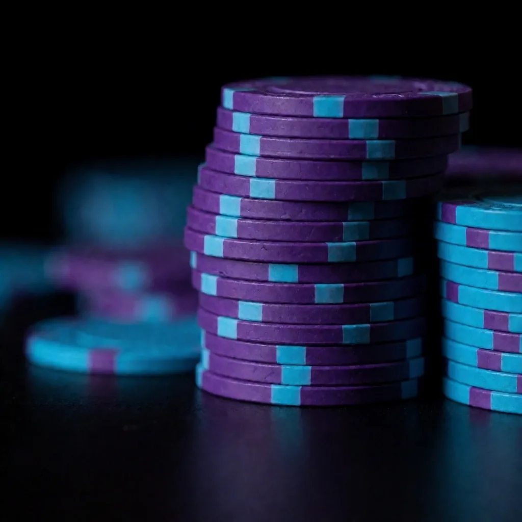 Stacked poker chips in violet and cyan on a reflective surface